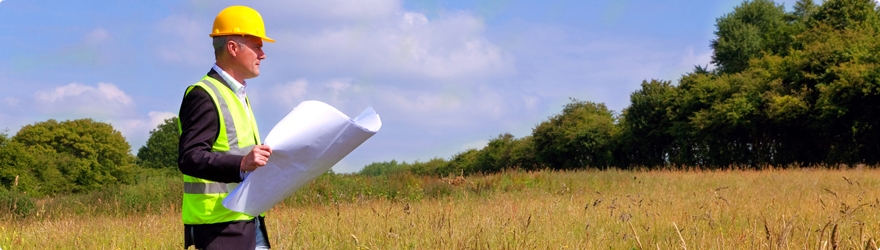 Land Surveyor Man wearing a hard hat, walking through a field